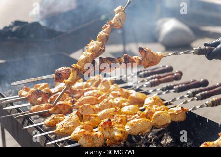 Saftiger, brutzelnder Schaschlik-Kebab, der an einem sonnigen Sommertag auf einem Holzkohlegrill im Freien gegrillt wird. Stockfoto