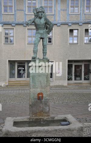 Holzträger von Bernhard Frydag, 1914, männliche Figur mit Korb mit Holz auf dem Rücken, Symbol für Forstwirtschaft, Holzfäller, Holz, Brunnen, wo Stockfoto