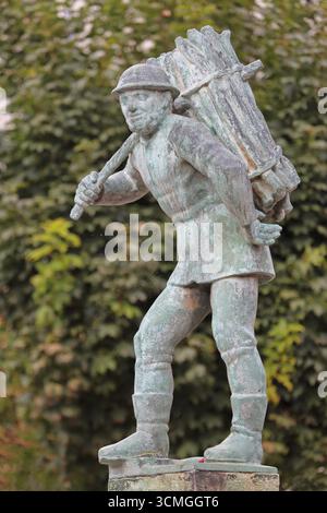 Holzträger von Bernhard Frydag, 1914, männliche Figur mit Korb mit Holz auf dem Rücken, Symbol für Forstwirtschaft, Holzfäller, Holz, Brunnen, wo Stockfoto