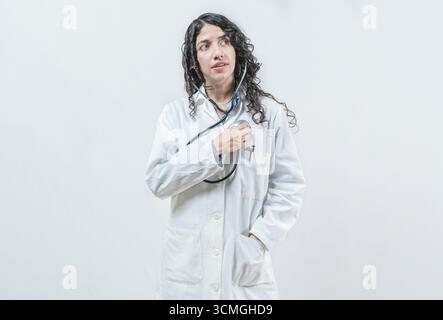 Doktor, der ihr Herz mit Stethoskop hört, isoliert. Ärztin mit Stethoskop auf der Brust, die auf ihr Herz hört Stockfoto