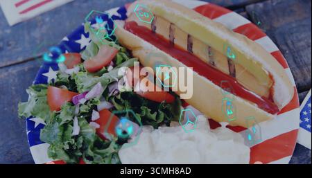 Mit patriotischem Teller mit Hot Dog mit Saucen, Kartoffelsalat auf Holztisch, Energienikonen Stockfoto