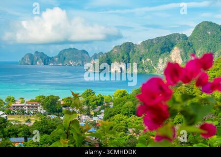 Luftaufnahme der türkisfarbenen Wasserbucht der tropischen Insel Ko Phi Phi Don in der Andamanensee, Krabi, Thailand mit Bougainvillea-Blume im Vordergrund. Ansicht Stockfoto