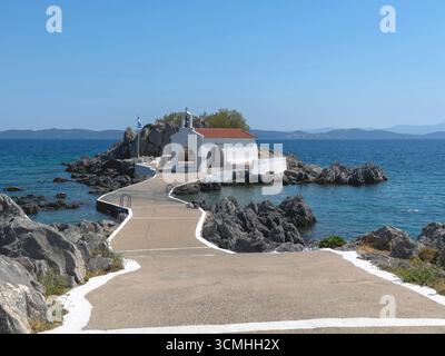 Agios Isidoros kleine Kirche, Insel Chios, Griechenland. Traditionelle Architekturkapelle auf einer felsigen Insel, die durch einen schmalen Betonwalkw mit dem Ufer verbunden ist Stockfoto