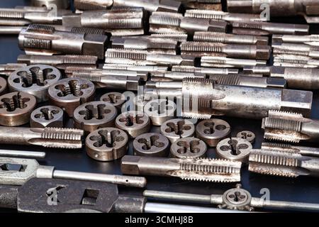 Gewindebohrer, Matrizen und Schraubenschlüssel für Gewindebohrer und Matrizen auf schwarzem Hintergrund. Manuelles Gewindewerkzeug. Stockfoto