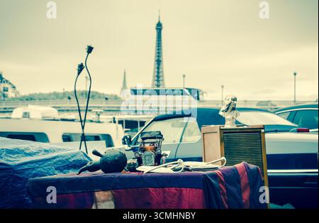 Flohmarkt in Paris, Frankreich. Oldtimer-Modell und anderes Zeug auf einem Stand mit Blick auf die seine-Ufer und den Eiffelturm. Retro-Foto. Stockfoto