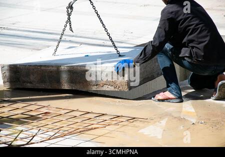 Die Arbeiter installieren eine große Betonabdeckung. Stockfoto