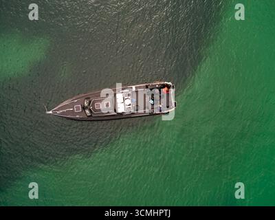 Blick hinunter auf ein kleines schwarzes Boot auf dem Meer in der Nähe der Isle of Coll, Argyll und Bute, Schottland Stockfoto