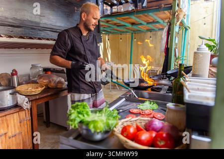 Koch grillt einen saftigen Burger über offener Flamme Stockfoto