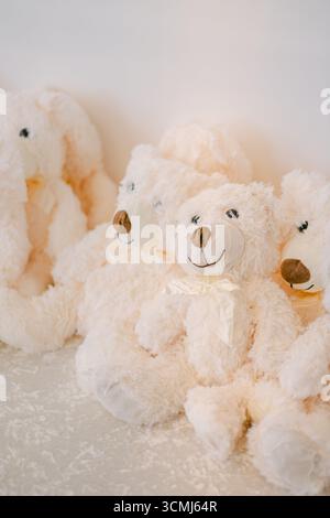Vier flauschige Teddybären sind ordentlich auf einer weichen Oberfläche platziert und strahlen Wärme und Komfort in einer hellen Umgebung aus. Stockfoto