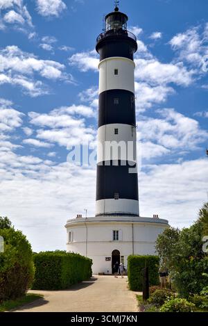 Pfad, der zum Eingang des Leuchtturms Phare de Chassiron führt, gesäumt von Büschen auf beiden Seiten unter klarem Himmel Stockfoto