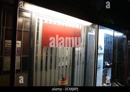 Nächtlicher Blick auf ein Schaufenster mit einem leeren roten Schild, ideal für Werbung. Stockfoto