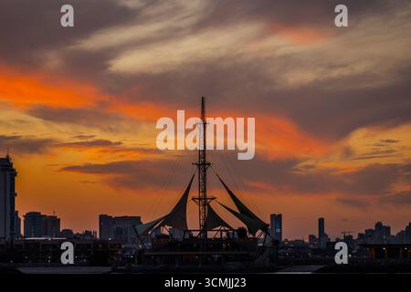 Der Freizeitkomplex Marina Waves mit seinen segelförmigen Baldachinen ist vor einem farbenfrohen Sonnenuntergangshimmel in Kuwait City, Kuwait, zu sehen. Kuwait City, Kuwait Stockfoto