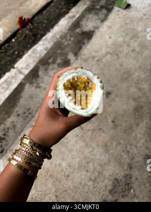 Nahaufnahme einer halben Passionsfrucht in der Hand, Tetebatu, Lombok, Indonesien Stockfoto