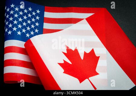Die Nationalflagge der USA und die Flagge Kanadas isoliert auf Schwarz. Ein Konzept der Beziehungen zwischen den USA und Kanada. Stockfoto