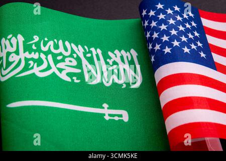 Die Nationalflagge Saudi-Arabiens und die US-Nationalflagge isoliert auf Schwarz. Ein Konzept der Beziehungen zwischen Saudi-Arabien und den USA. Stockfoto