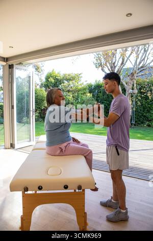 Verschiedene Therapeuten und Patienten, die durch Glastüren sitzende Arme auf Therapientisch Strecken Stockfoto