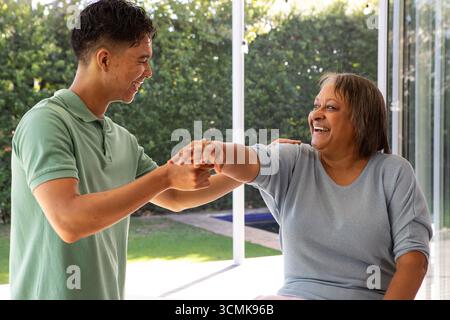 Hispanische Großmutter und Enkel lächeln, Arm auf der Terrasse durch eine Glasschiebetür Stockfoto