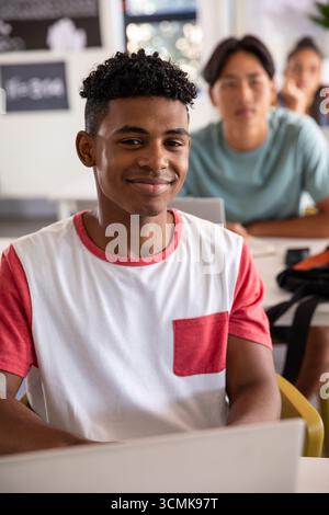 Verschiedene Teenager-Klassenkameraden lernen mit Laptop und Notizbüchern im Unterricht mit Tafel Stockfoto