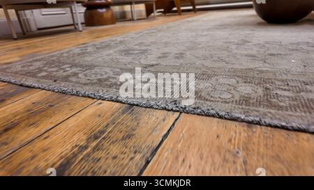 Nahaufnahme eines schmutzigen Teppichs auf Holzboden Stockfoto
