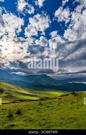 Wunderschöne Landschaft, in der die Sonne durch Wolken über grünen Hügeln und Tälern in den Pyrenäen in der Nähe von Ancizan, Frankreich, scheint Stockfoto