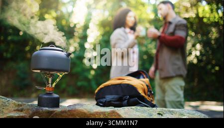 Reisen Sie Wasserkocher, Paare und Natur mit Rucksack zum Wandern, Ausruhen oder Campen im Wald. Ausrüstung, Ausrüstung oder Kaffee mit Mann und Frau zum Trekking Stockfoto