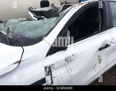 Ein weißer Wagen ist unfallartig. Autounfall auf der Straße. Autounfall auf der Straße. Beschädigtes Fahrzeug. Kfz-Versicherungskonzept. Fahrzeug wird stark beschädigt b Stockfoto
