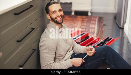 Porträt, Sanitär und Mann zu Hause mit Werkzeugkasten, Wartung oder Prüfung an Rohren. Lächeln, Routineinspektion und Klempner in der Küche mit Ausrüstung, Leck Stockfoto
