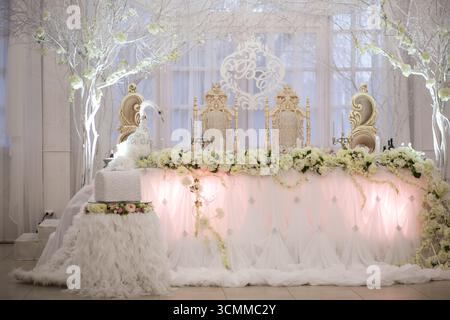 Ein wunderschön gestalteter Hochzeitsempfang zeigt ein üppiges Blumendesign in sanften weiß- und Pastelltönen. Stockfoto
