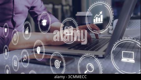 Arbeitender reifer asiatischer Mann mit violettem Hemd, der Daten auf Laptop im Büro analysiert, mit Datensymbolen Stockfoto