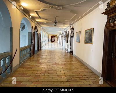 Einsiedeln, Schweiz - 28. September 2022: Langer, detaillierter Korridor in einem alten Gebäude im Kloster Einsiedeln, Schweiz mit Bogensäulen und Kunstwerken Stockfoto