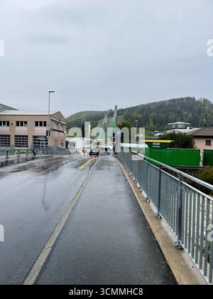 Einsiedeln, Schweiz - 28. September 2022: Städtische Straße bei regnerischem Wetter mit Hügeln und Gebäuden in der Ferne in Einsiedeln, Schweiz Stockfoto