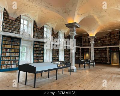 Einsiedeln, Schweiz - 28. September 2022: Elegantes Bibliotheksinnere mit kunstvoller Decke, Bücherregalen und warmem Tageslicht im Kloster Einsiedeln Stockfoto