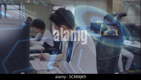 Hispanische Frau in weißer Strickjacke, blaues Hemd auf Notizblock im Büro, mit digitalen Overlays Stockfoto