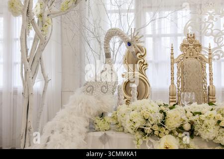 Wunderschön gestalteter Hochzeitstisch mit einem kunstvollen Pfau, der mit Perlen und Federn verziert ist. Der Tisch zeigt elegante Blumenarrangements, perfec Stockfoto