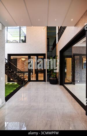 Geräumiges und helles, modernes Innenleben mit großen Glastüren, klaren Linien und einer minimalistischen Ästhetik mit Innengrün, luxuriöser Inneneinrichtung Stockfoto