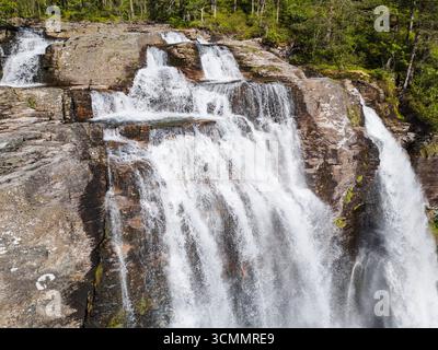 Aus der Vogelperspektive sehen Sie einen mächtigen Wasserfall, der über zerklüftete Felsen in einer üppig grünen Waldwildnis kaskadiert. Stockfoto