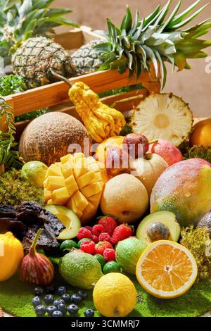 Lebendige tropische Fruchtfülle in einer Holzkiste wurden Früchte wie Ananas, Mango und andere Früchte zusammen in eine Holzkiste gelegt Stockfoto
