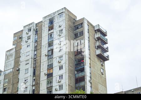 Apartmenthaus aus der jugoslawischen Zeit: Die Fassade mit Balkonen und Klimaanlage. Sozialistische Wohnarchitektur aus Belgrad, Serbien Stockfoto
