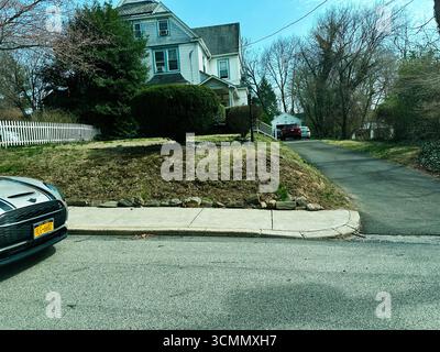 Jenkintown, Pennsylvania, USA - 01. April 2025: Vorstadthaus mit schrägen Einfahrten, Grün und ruhiger Nachbarschaft. Stockfoto