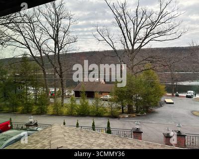 Jenkintown, Pennsylvania, USA - 01. April 2025: Stadtviertel am See mit Bäumen, geparkten Autos und bewölktem Himmel in der Natur. Stockfoto