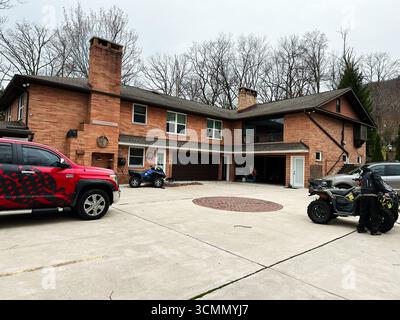 Jenkintown, Pennsylvania, USA - 1. April 2025: Ein Vorstadthaus mit Fahrzeugen und offener Garage in einer Einfahrt. Stockfoto