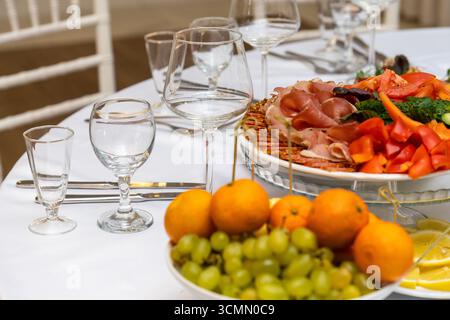 Platten mit verschiedenen Fleisch- und Obstsorten auf festlichem Tisch für eine Feiertags- oder Dinnerparty. Stockfoto