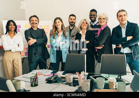Ein erfolgreiches und vielseitiges Team von Geschäftsleuten aus mehreren Generationen lächelt und posiert für ein Gruppenporträt mit überkreuzten Armen in einem modernen Unternehmen Stockfoto