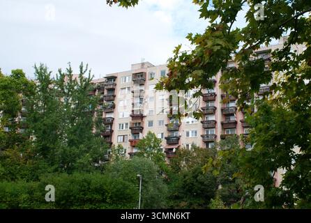 Große Apartmentblöcke erheben sich hinter einem grünen Park mit Bäumen und Rasen. Typisch osteuropäische Wohnsiedlung mit sozialistischer Architektur. Stockfoto