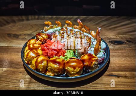 Gourmet-Sushi-Platte: Ein exquisites Arrangement aus verschiedenen Rolls, Nigiri und Tempura-Garnelen, kunstvoll präsentiert. Reichhaltiges Sortiment an frischen Sushi, gebacken Stockfoto