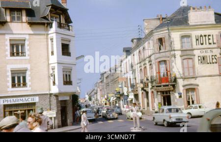 Geschäftige Straßenszene in Le Croisic, Loire-Atlantique, Frankreich, 1963 mit Hôtel des Familles, Oldtimern und uniformierten Verkehrsoffiziern. Stockfoto