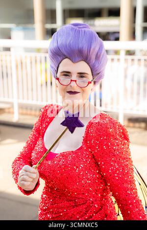 Eine ältere Cosplayer, die als Fee gekleidet ist, mit Kleid, Perücke und Zauberstab, die glücklich und zufrieden aussieht Stockfoto