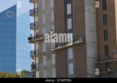 San Antonio, USA. September 2025. Arbeiter auf zwei hängenden Gerüsten mit dem Frostturm im Hintergrund in San Antonio, Texas, USA, am 16. September 2025. Der Frost Tower wurde von Pelli Clarke Pelli Architects entworfen. Als es 2019 eröffnet wurde, war es das erste Bürohochhaus, das seit 1989 in der Innenstadt von San Antonio gebaut wurde. (Foto: Carlos Kosienski/SIPA USA) Credit: SIPA USA/Alamy Live News Stockfoto