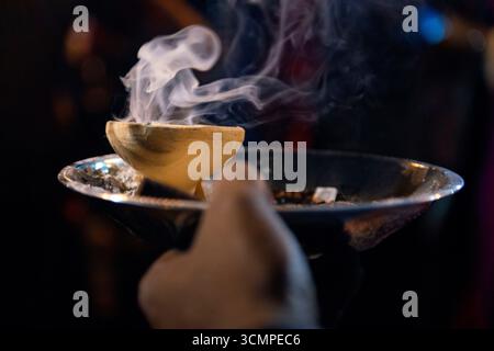 Geweihter, der während des Thaipusam-Festivalrituals Weihrauch hält, wobei Rauch in der Luft aufsteigt Stockfoto