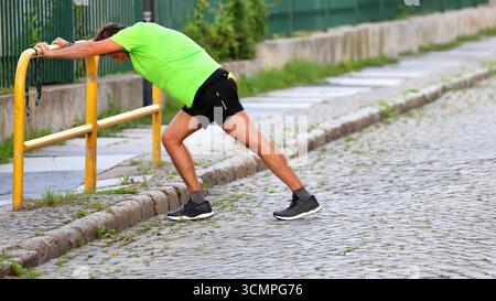 Mann, der sich auf der Straße gegen ein Geländer ausdehnt Stockfoto